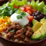 Close-up of a beef burrito bowl with seasoned ground beef, rice, beans, and fresh toppings.